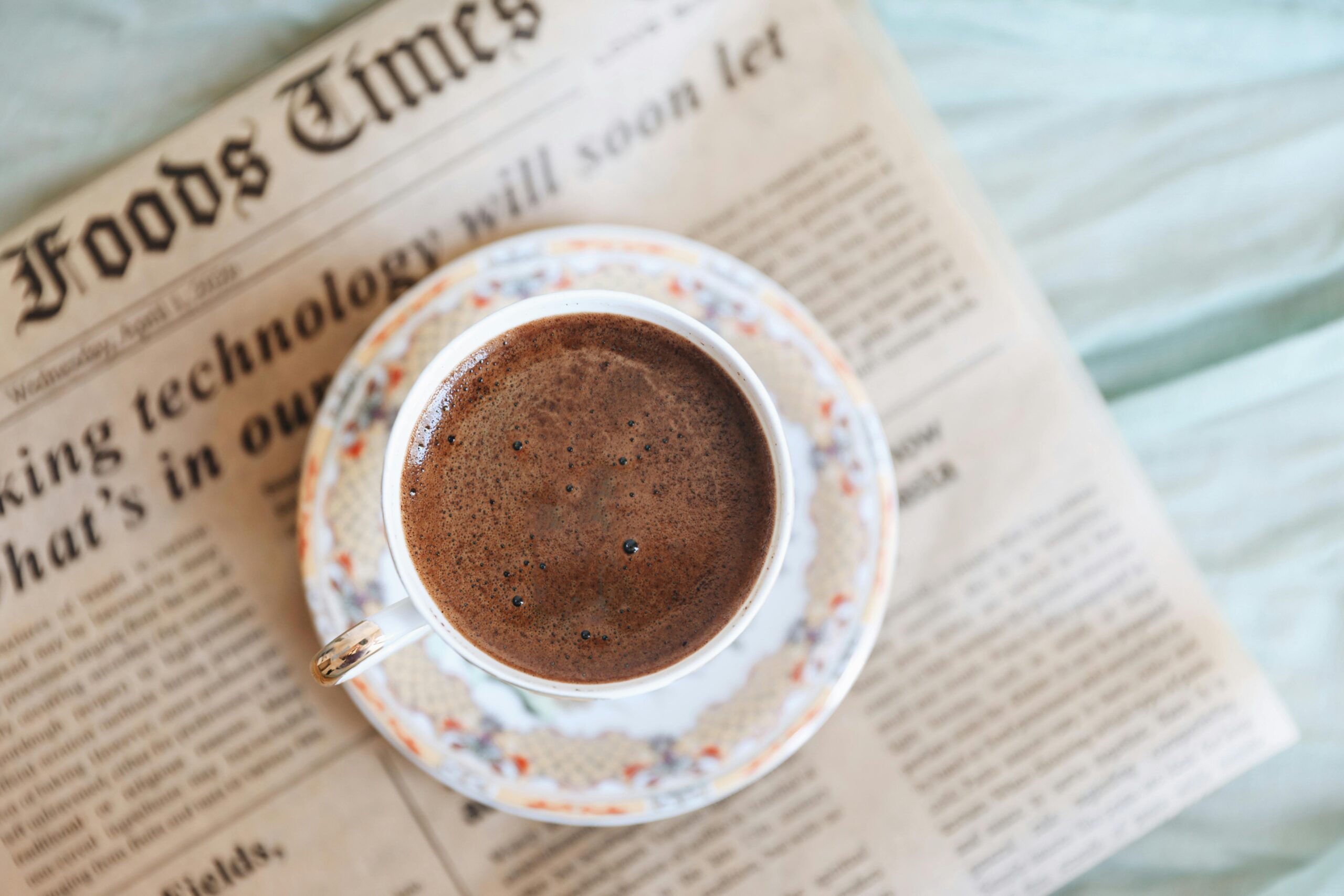 Top view of a black coffee cup on an old newspaper, perfect for a cozy morning.